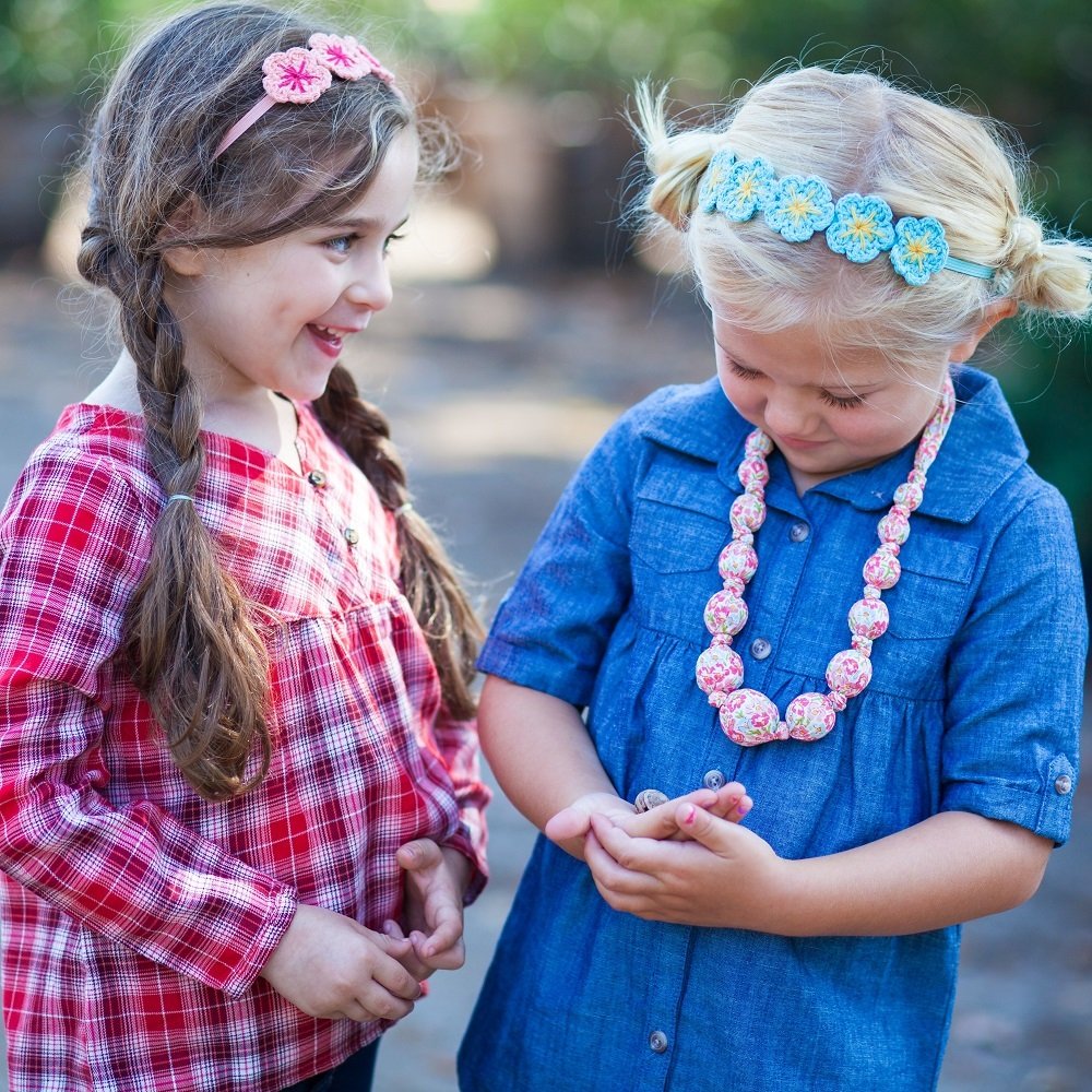 Girls wearing knit flower crown headbands in pink and blue with yellow centers