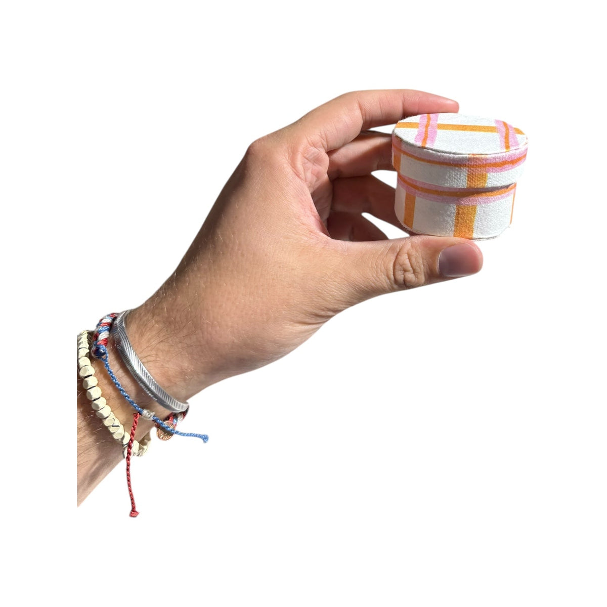 Hand holding a round handmade recycled paper gift box with multicolor plaid top and rim.