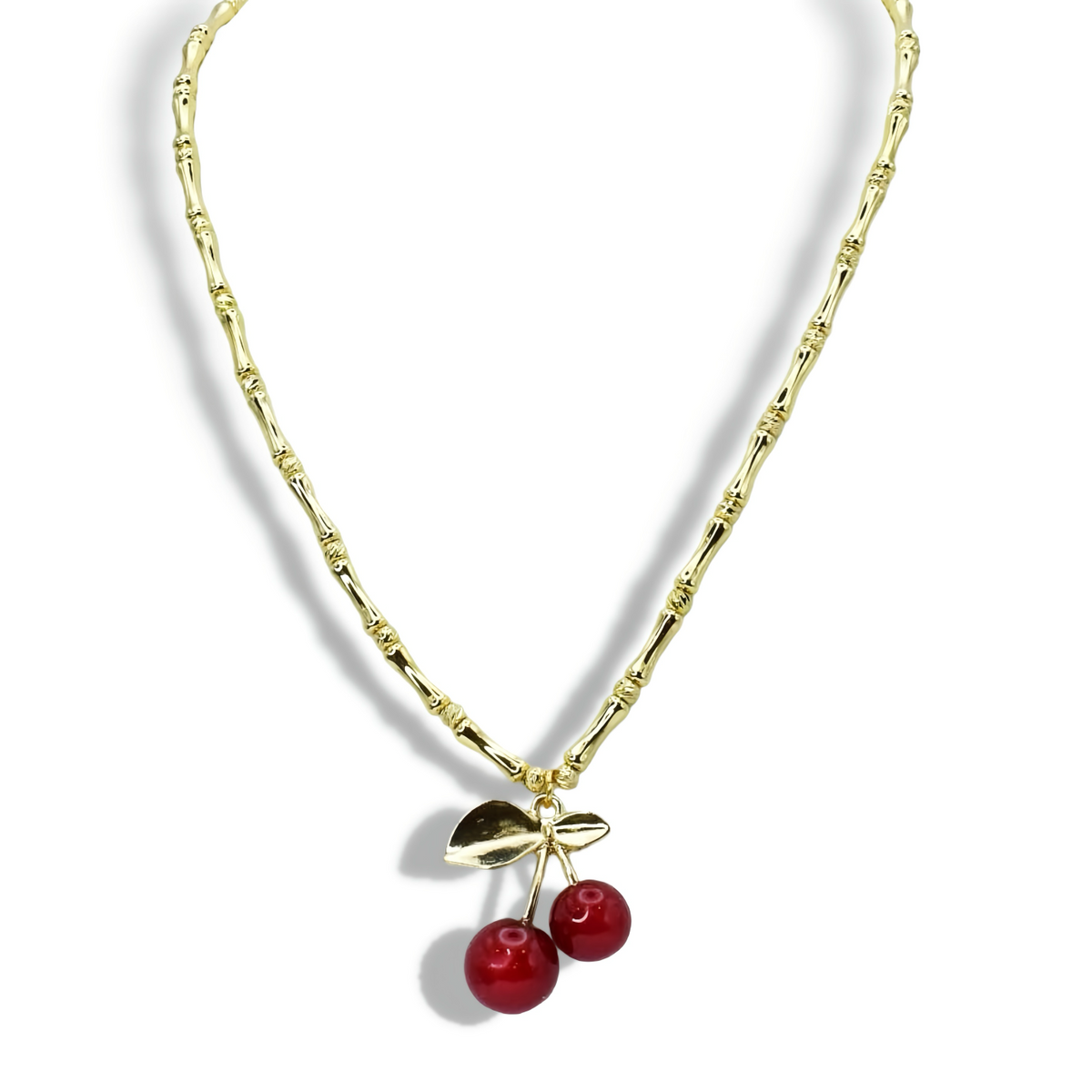 Gold-tone beaded necklace with leaf pendant and two red cherry bead drops