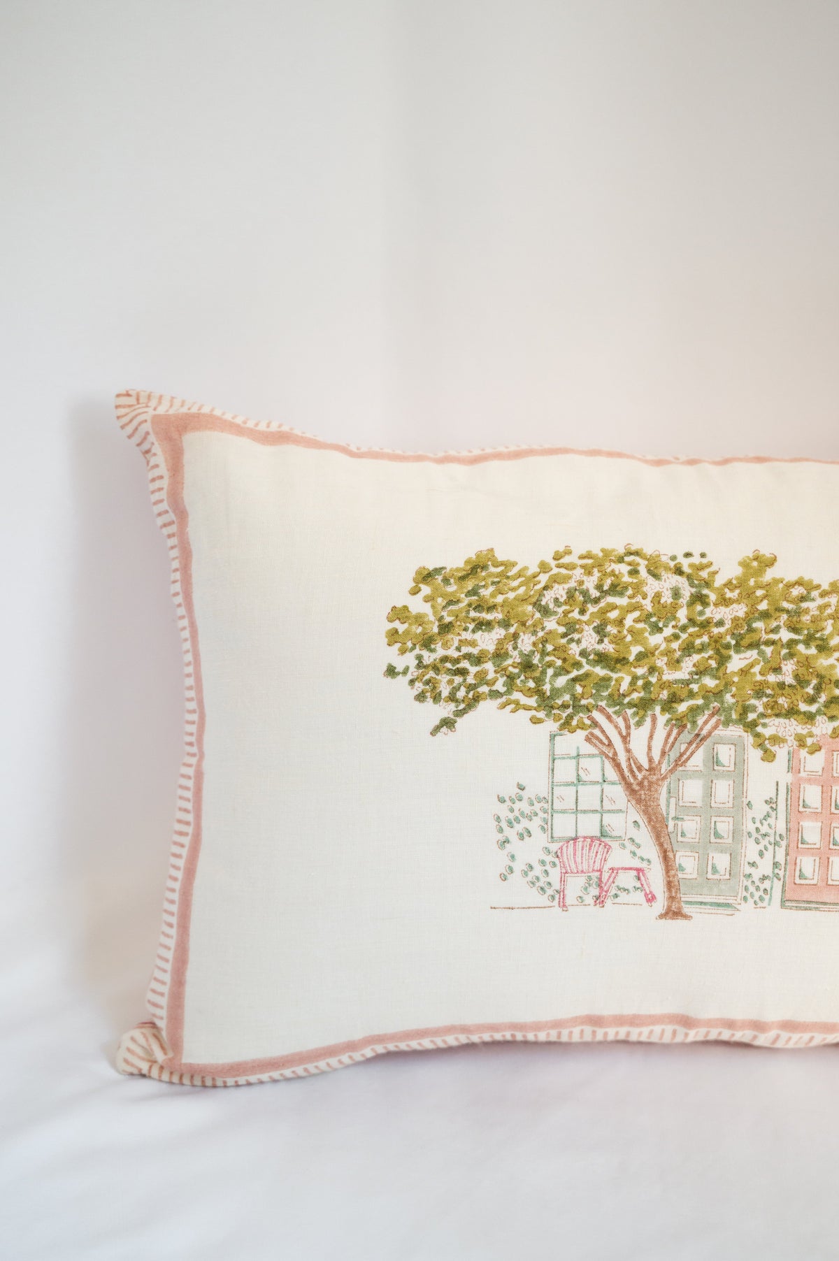 Block print cushion close-up of tree-and-house print with pink stitched border