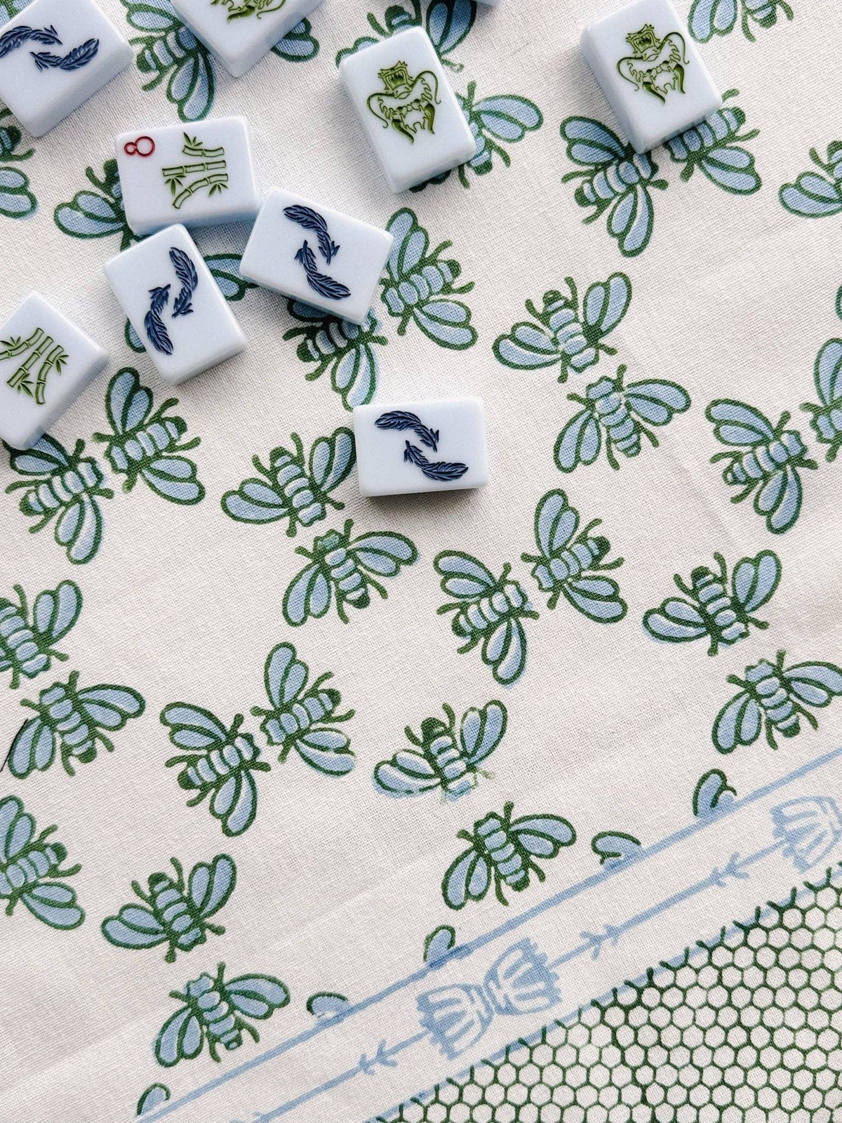 Table throw fabric with repeating blue and green floral pattern and light blue trim border.