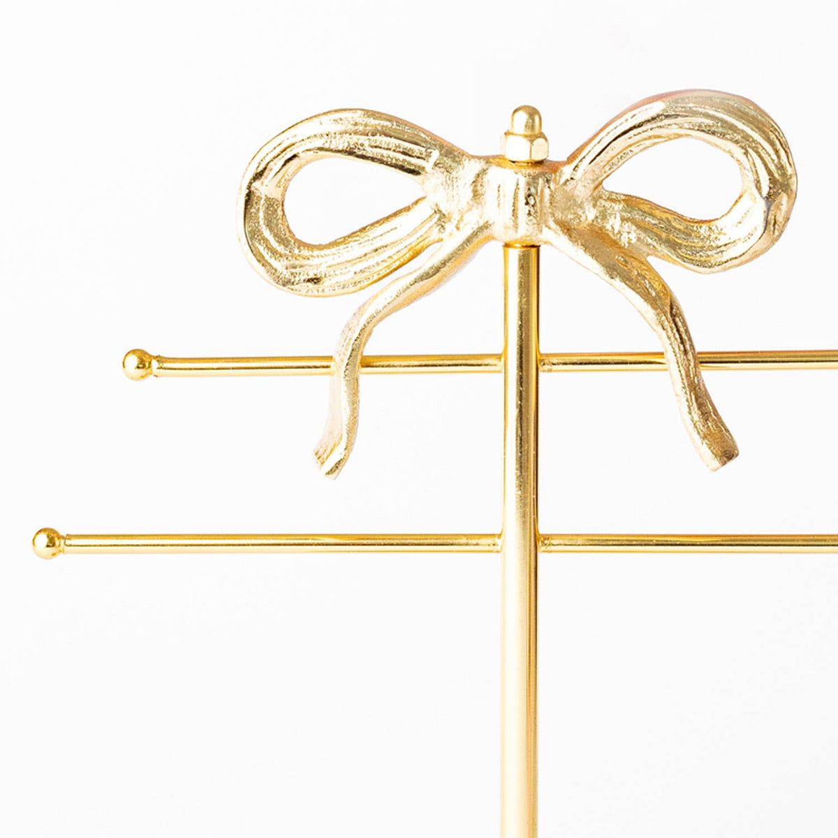 Gold-tone bow jewelry holder close-up of ribbon-style bow on vertical stand