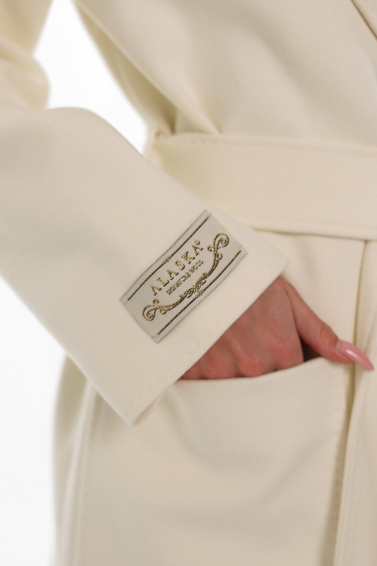 Close-up of the ivory overcoat cuff label, belt and patch pocket