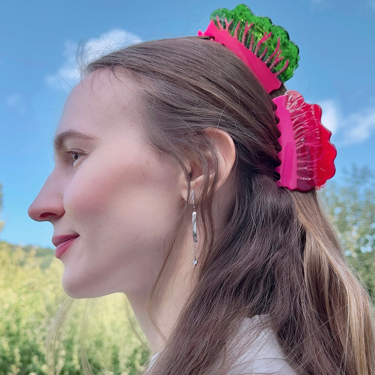 Pink and green hair claw clipped on brown hair at the side
