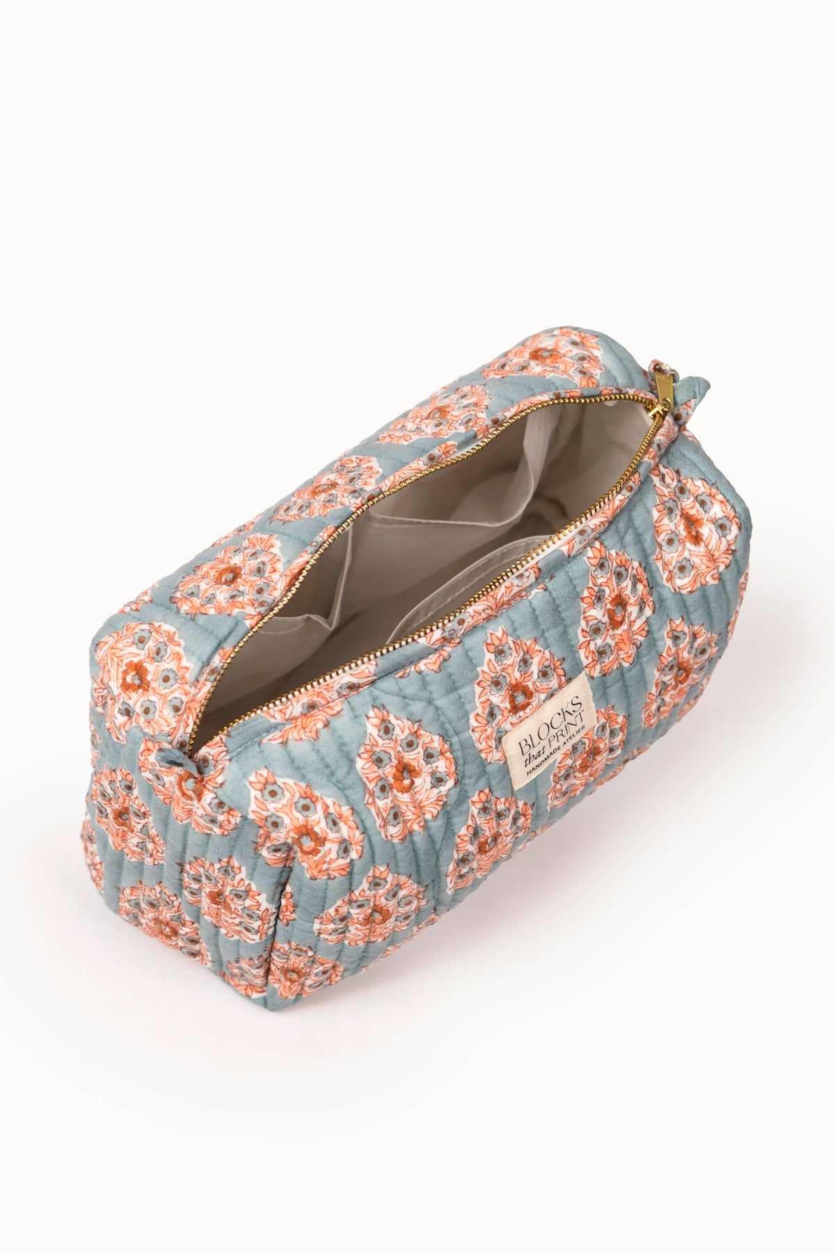 Quilted travel pouch with terracotta buta block print; open zip shows gray interior lining