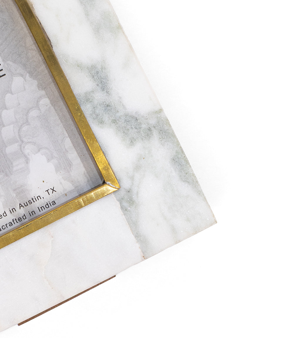 White marble arched frame corner with brass-toned edge inlay, angled close-up