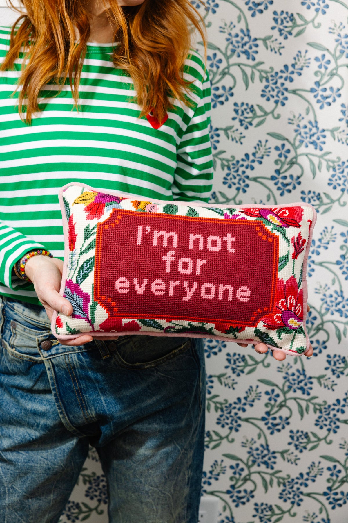 Red needlepoint pillow with floral border and "I'm not for everyone" stitched message