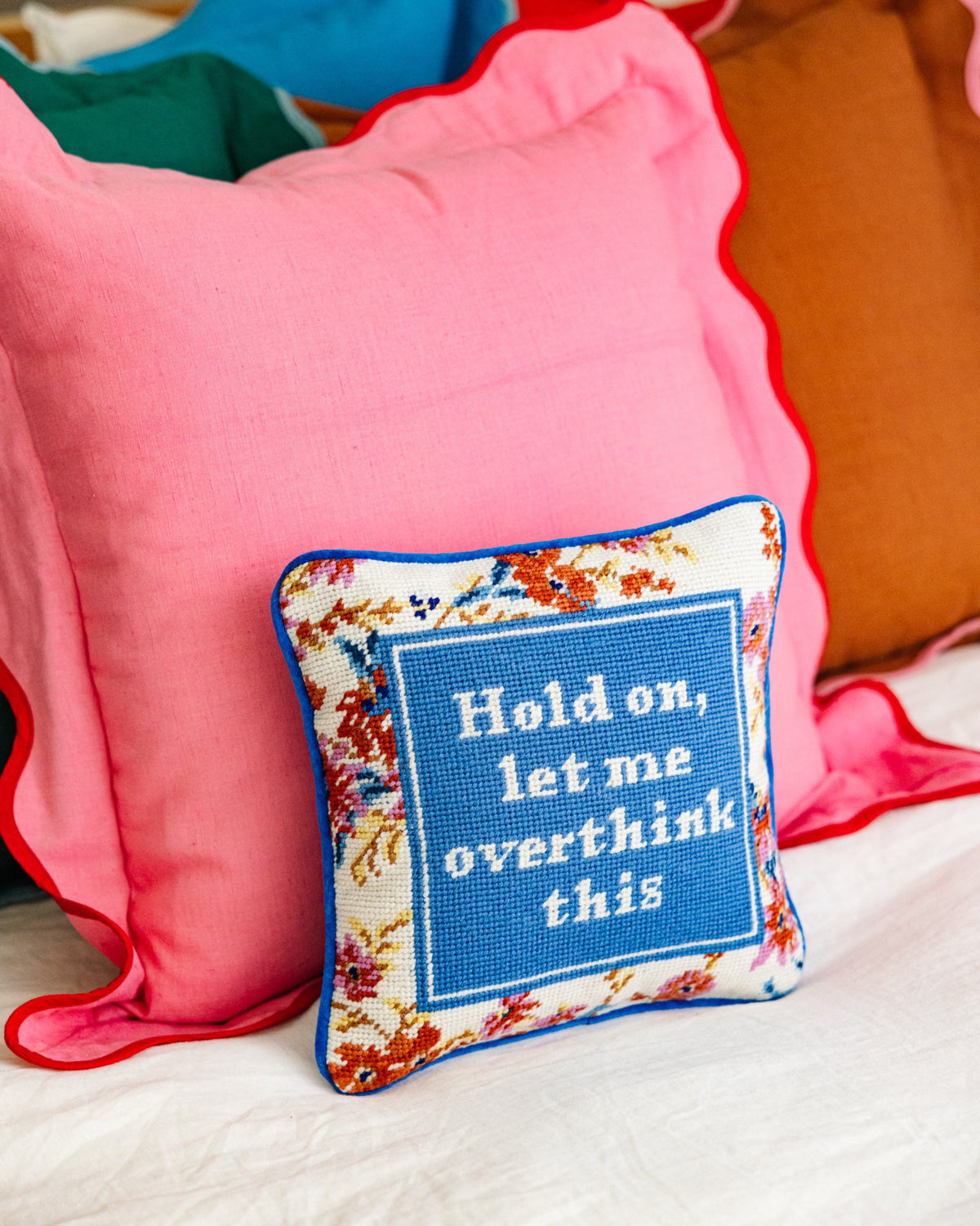 Needlepoint pillow with blue embroidered quote panel and colorful stitched border