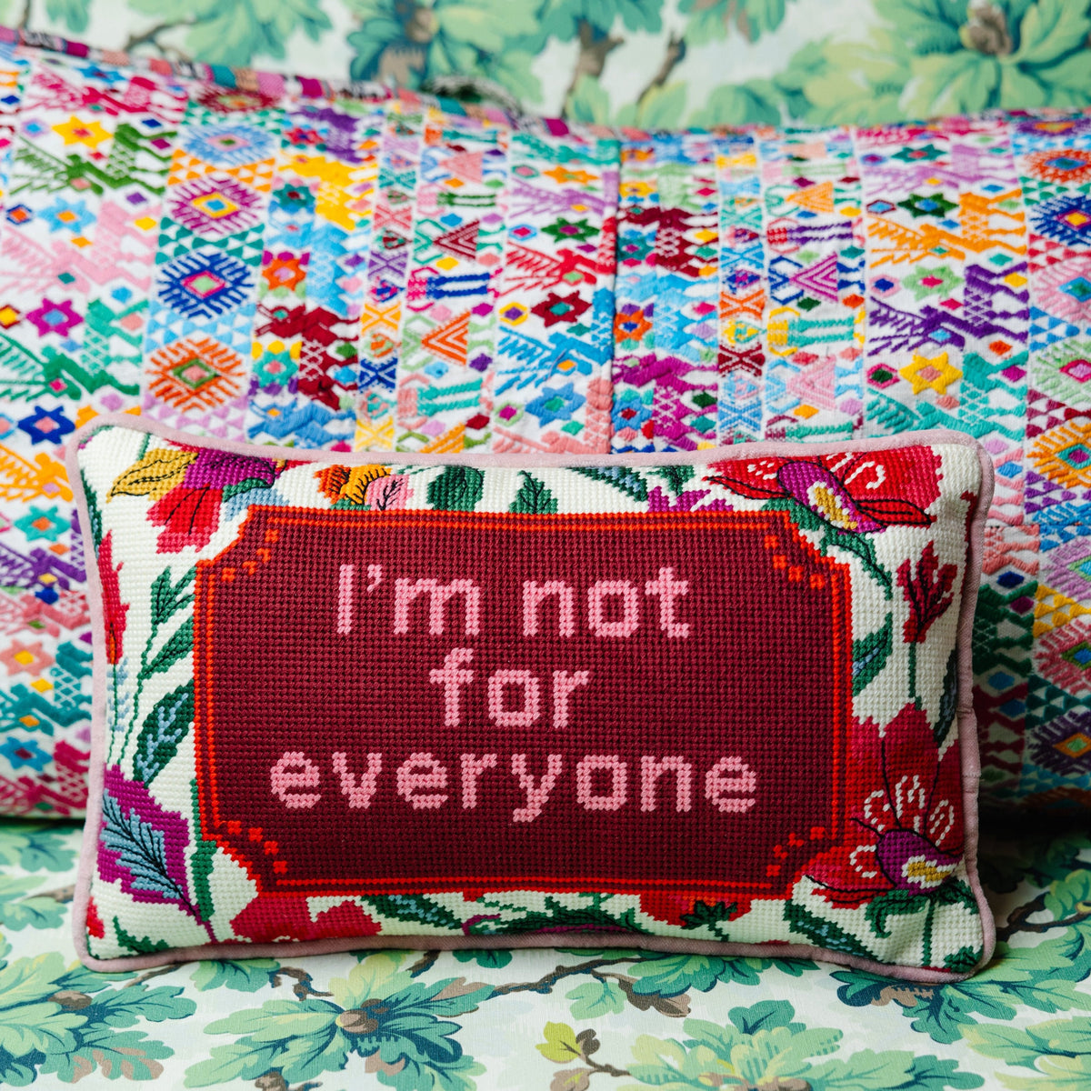 Red needlepoint throw pillow with floral border, "I'm not for everyone" needle-stitched text