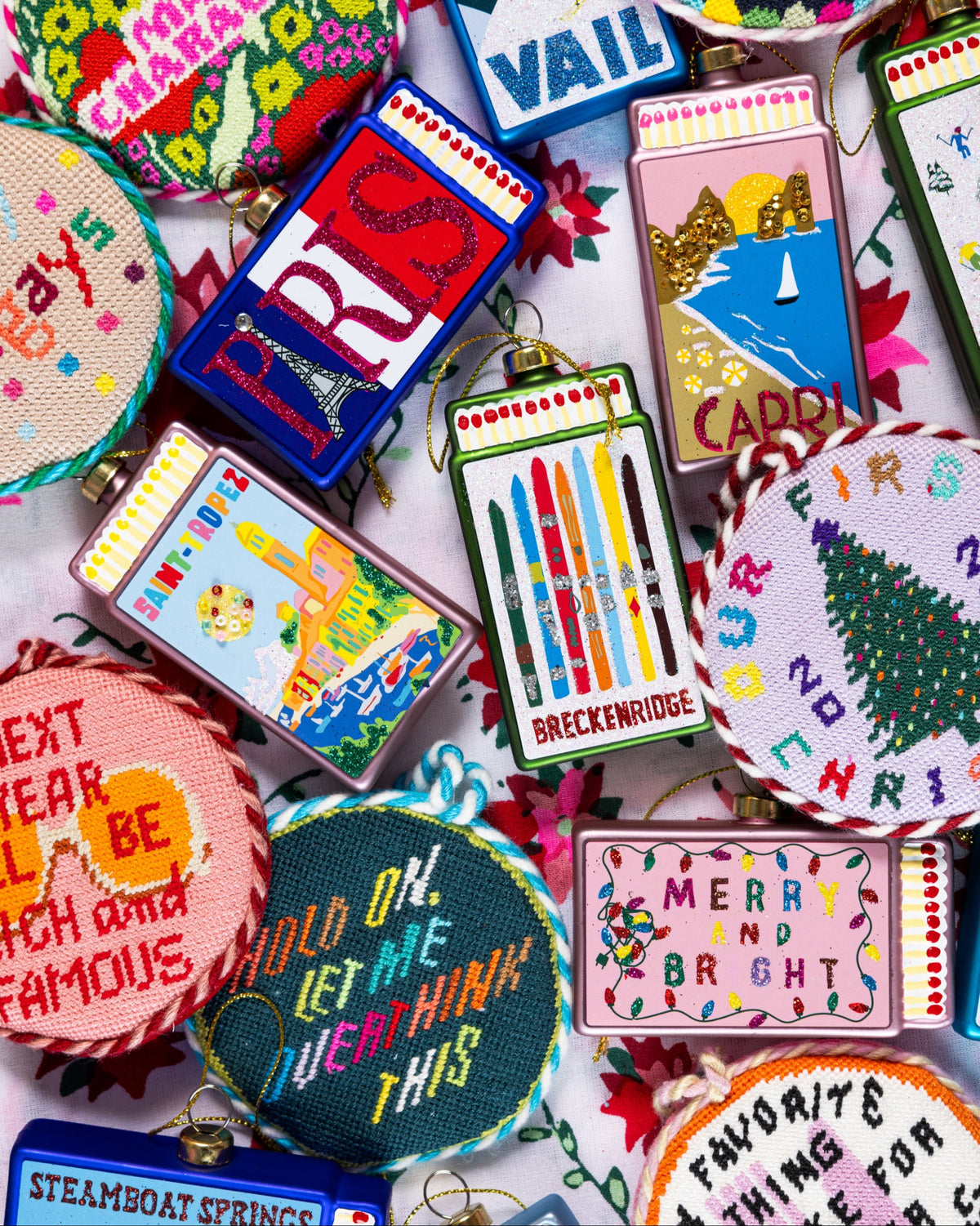 Assorted matchbook ornaments with colorful beach-themed illustrations and gold loops