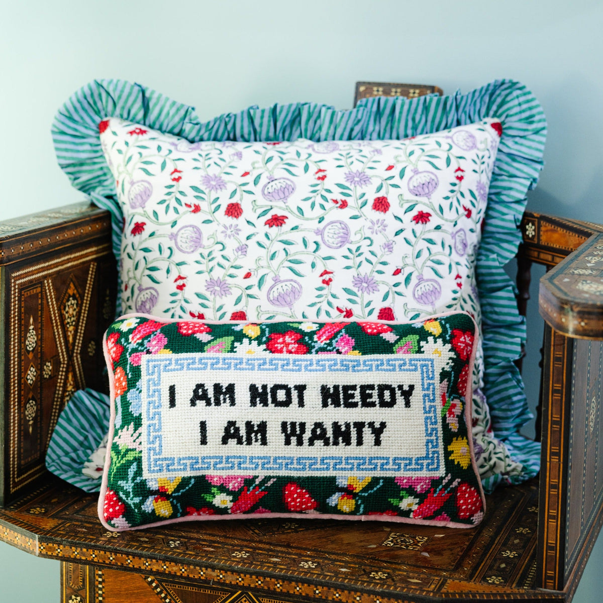 Needlepoint decorative pillow with "I AM NOT NEEDY" and "I AM WANTY" stitched on green