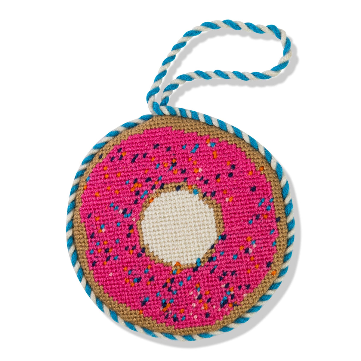 Needlepoint donut ornament with pink stitching, blue border, white center, hanging loop