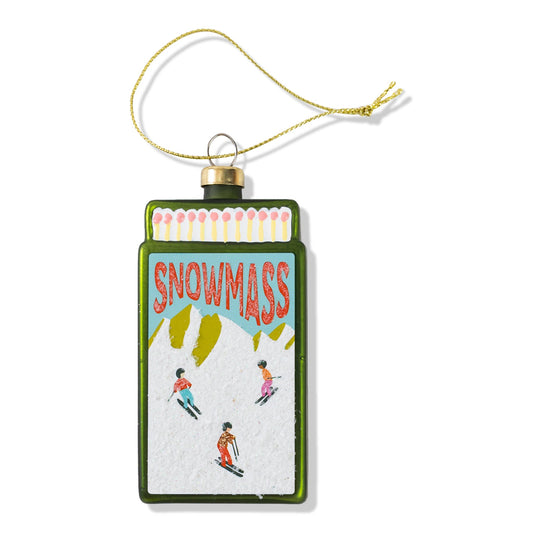 Matchbook-style Christmas ornament with 'SNOWMASS' ski scene, gold cap and loop