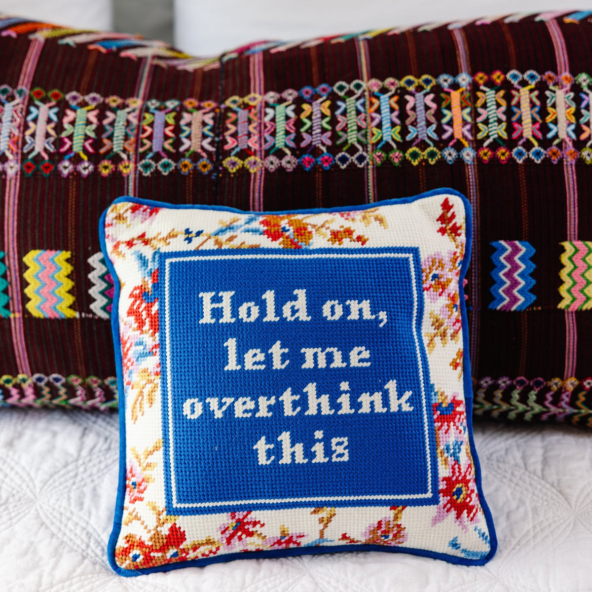 Needlepoint throw pillow with blue embroidered quote panel and multicolor floral edging