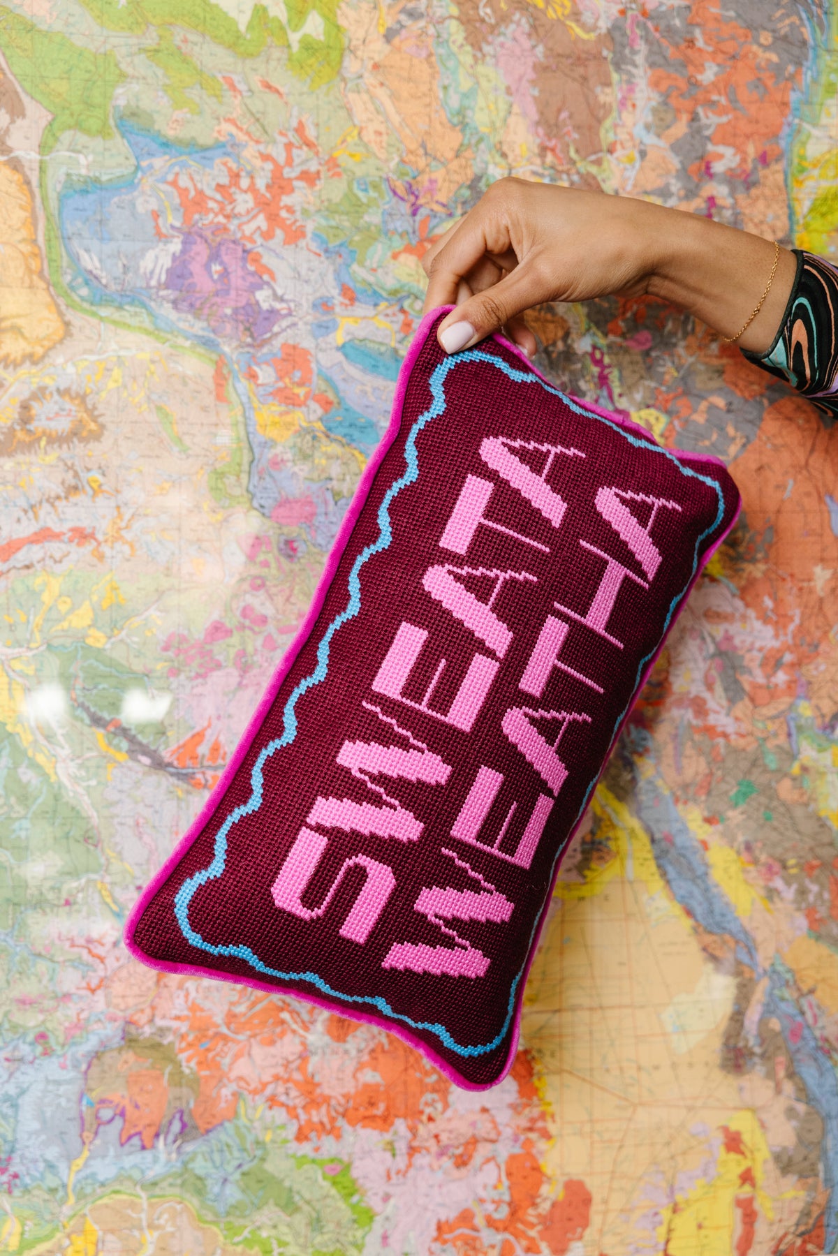 Purple needlepoint pillow with pink 'SWEATA WEATHA' letters