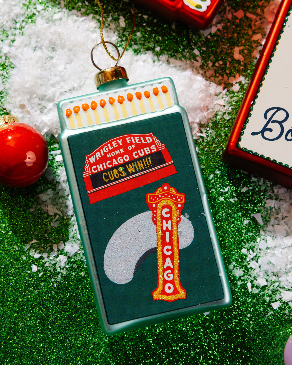 Teal Chicago Cubs matchbook ornament with hanging loop, on green tinsel