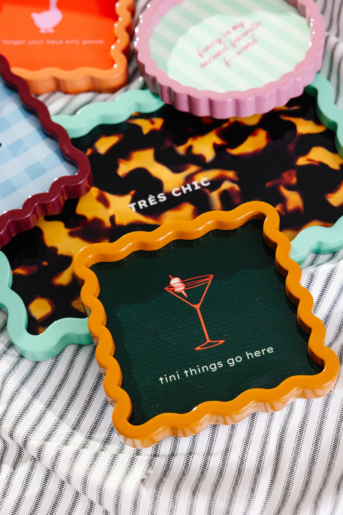 Scalloped lacquer tray with orange rim and dark green center, martini logo and “tini things go here”