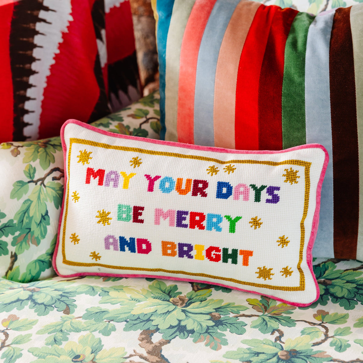 Needlepoint pillow with 'May your days be merry and bright' text and pink border