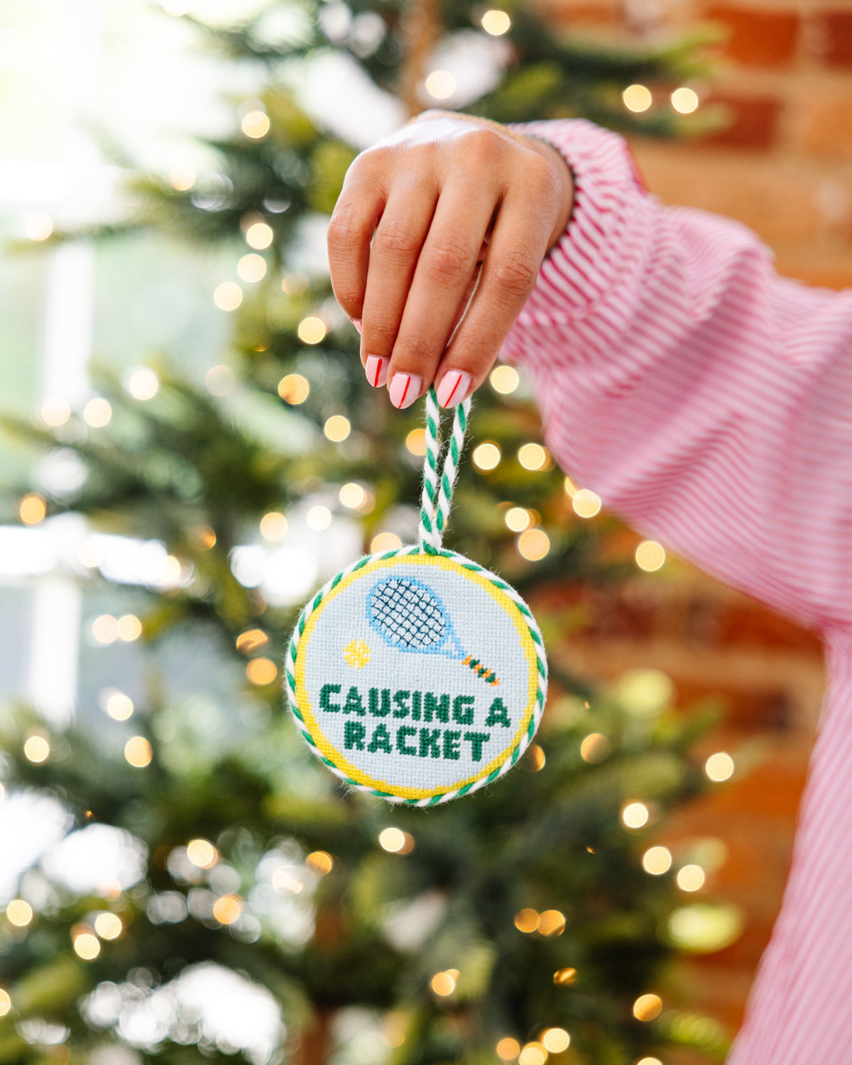 Round needlepoint Christmas ornament with blue bird motif and green-striped hanging cord