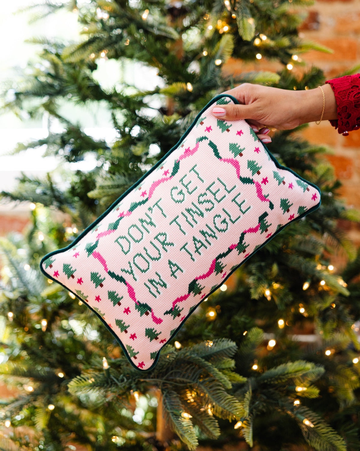 Handheld needlepoint throw pillow with pink-and-green embroidery, "DON’T GET YOUR TINSEL"