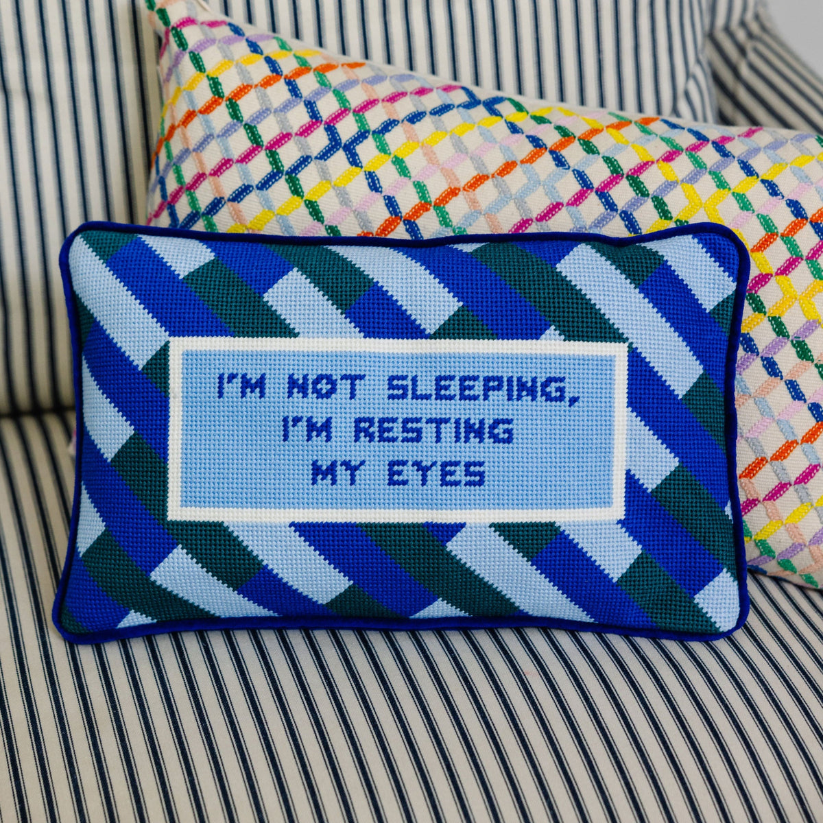 Needlepoint resting eyes pillow with blue geometric pattern and “I'm resting my eyes” text