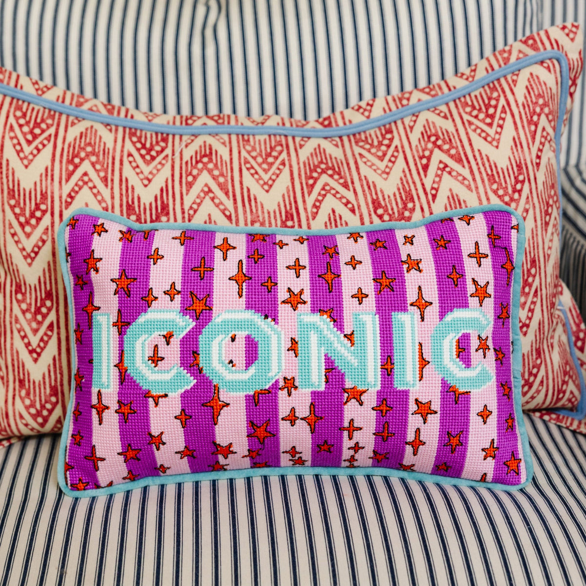 Needlepoint accent pillow with purple stitched front, teal letters, and star-and-cross motifs