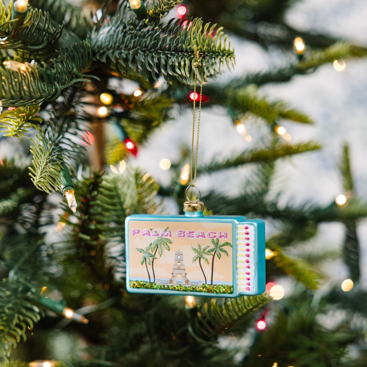 Palm Beach matchbook ornament hanging on a Christmas tree with multicolor edge dots