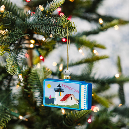Provincetown matchbook ornament hanging on pine branch with gold cord