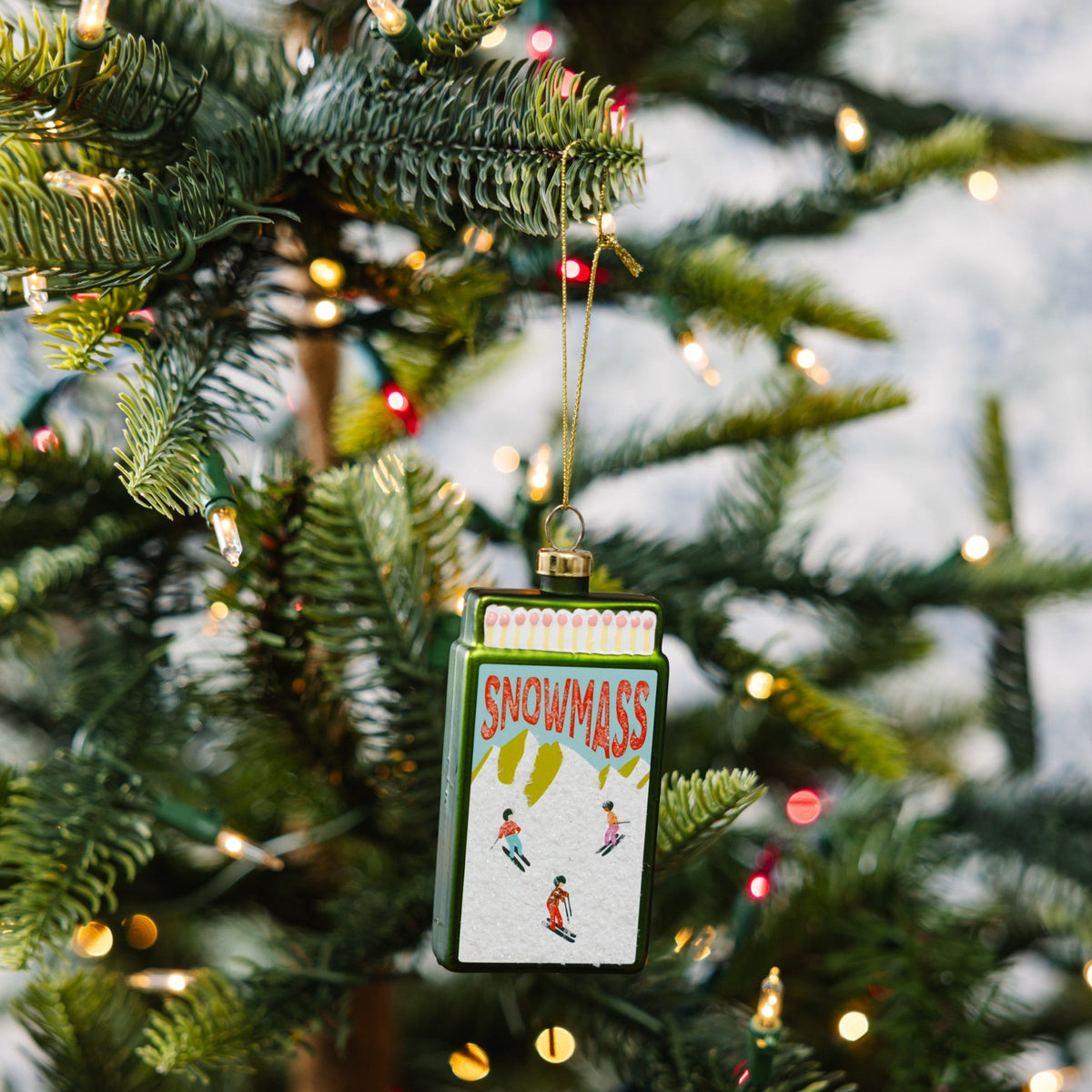 Snowmass matchbook ornament hanging on a gold cord from a Christmas tree