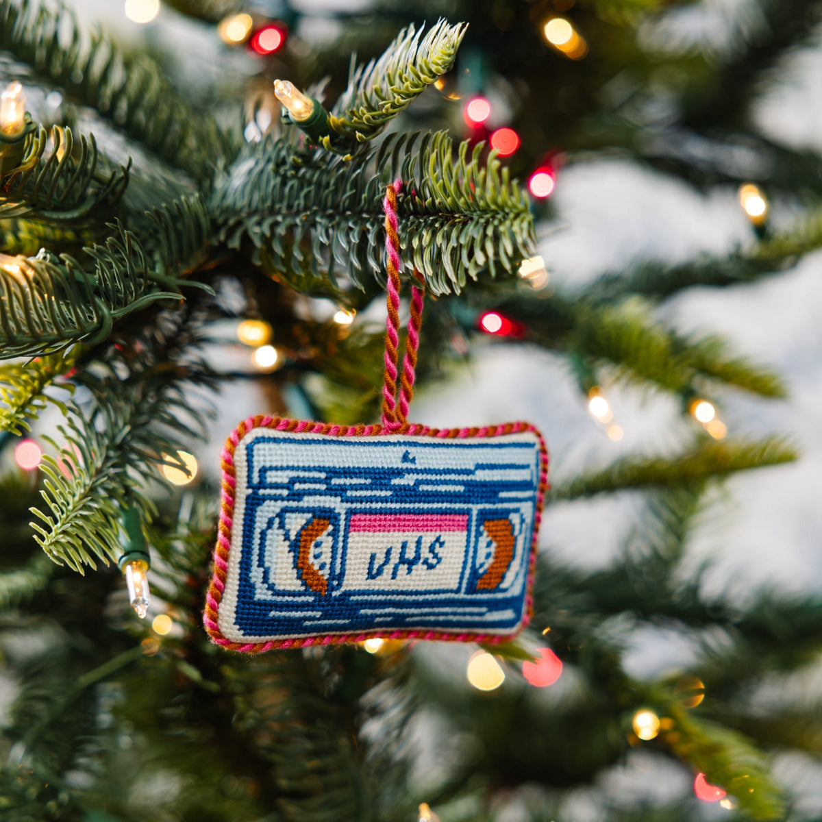 Needlepoint VHS tape ornament hanging from braided cord, blue stitched cassette design