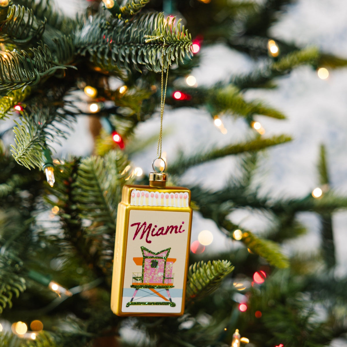 Hanging matchbook ornament with 'Miami' print, colorful top border, and gold cord loop