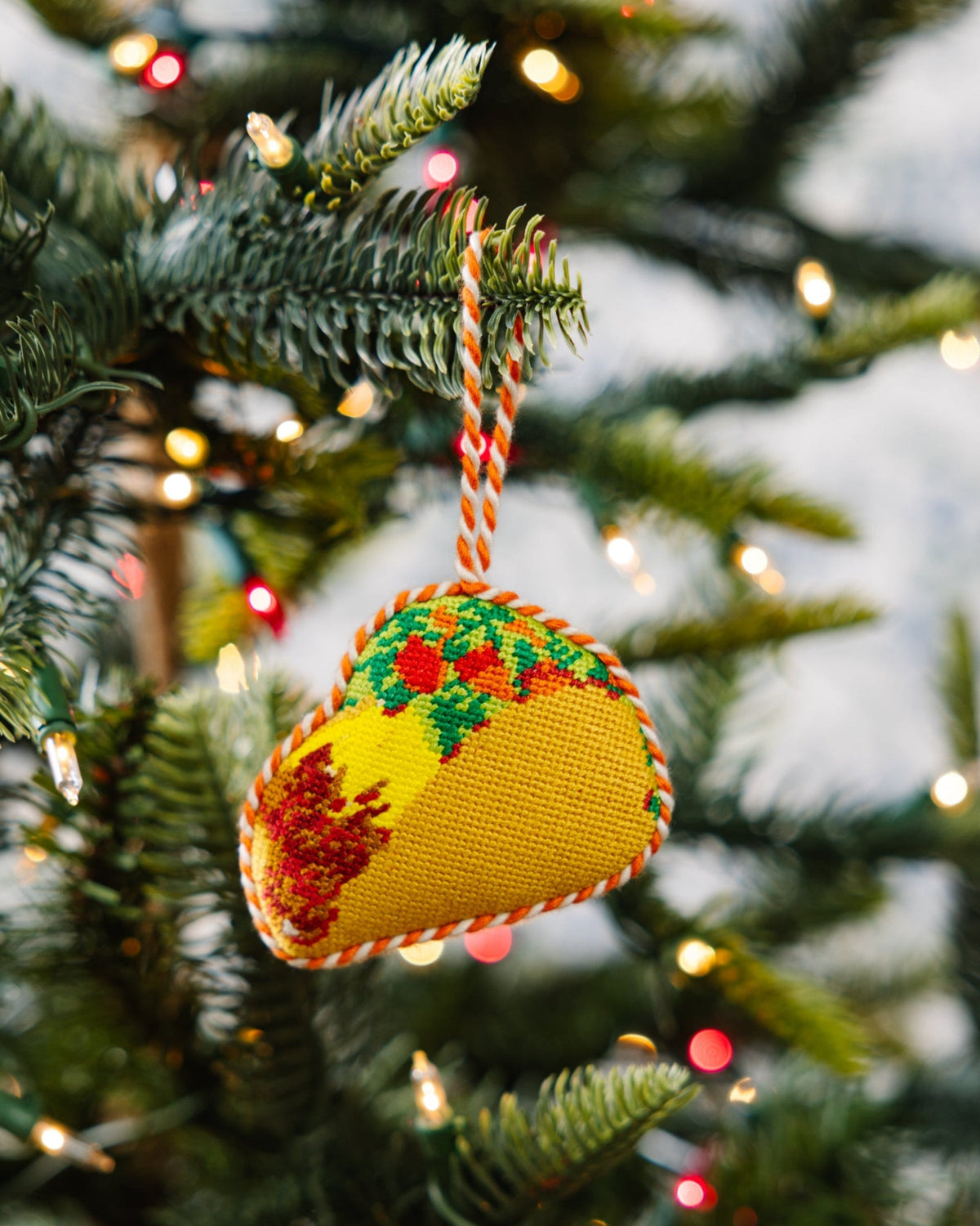 Hanging needlepoint taco ornament with multicolor stitched filling and shell