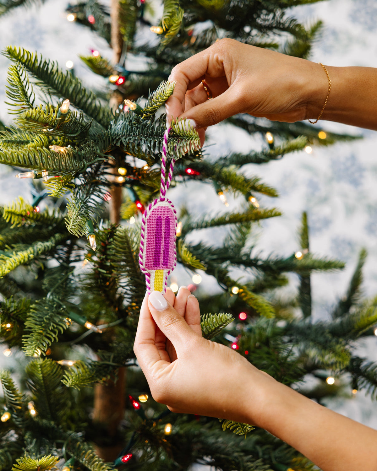 Needlepoint popsicle ornament on tree branch, pink purple stripes with yellow base