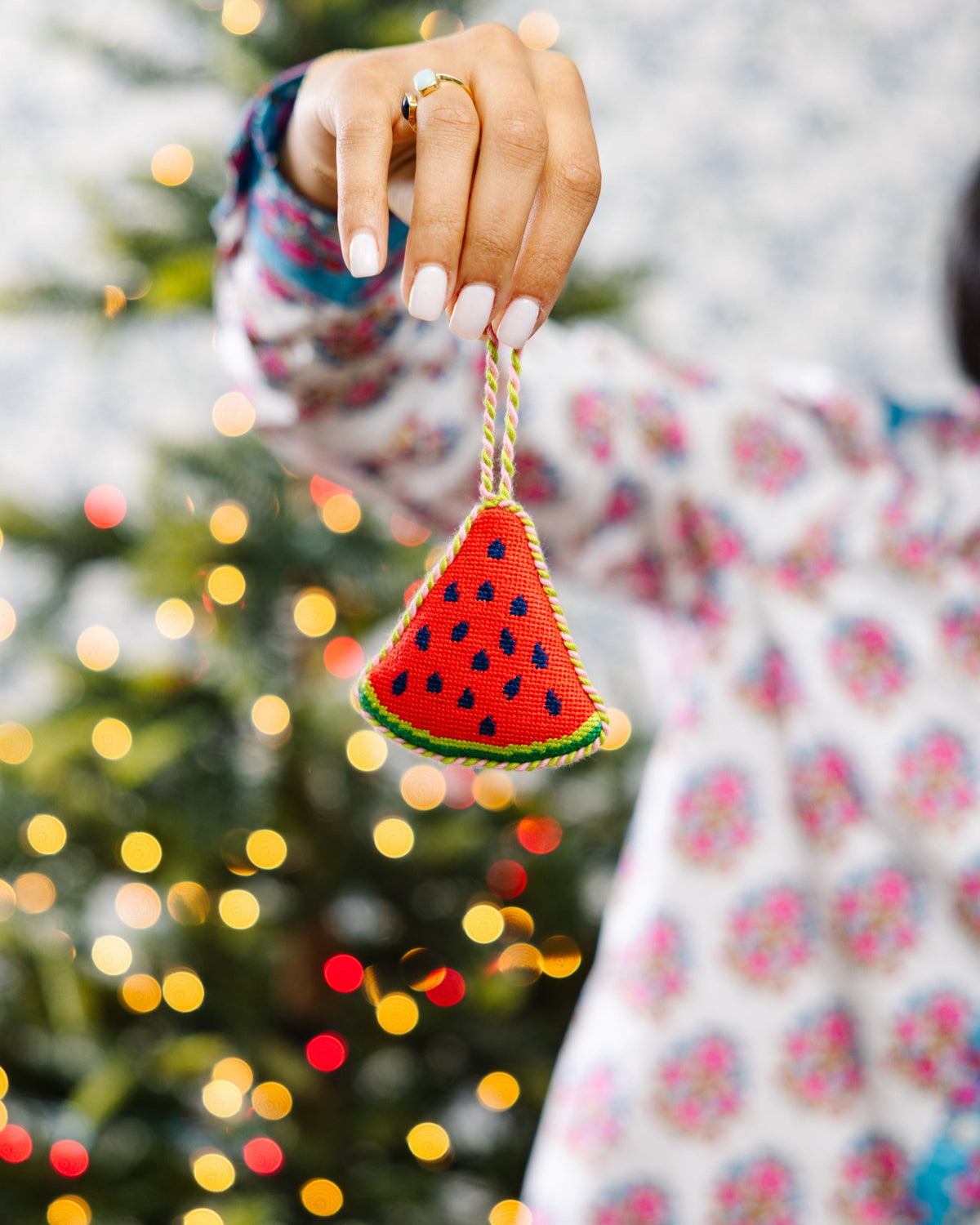 Watermelon needlepoint ornament held by hand, red triangular slice with blue seeds and green edge