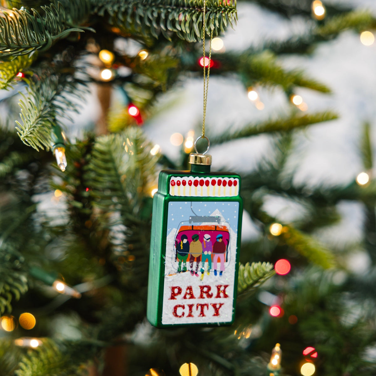 Park City matchbook ornament hanging on a tree, green frame, and PARK CITY text.