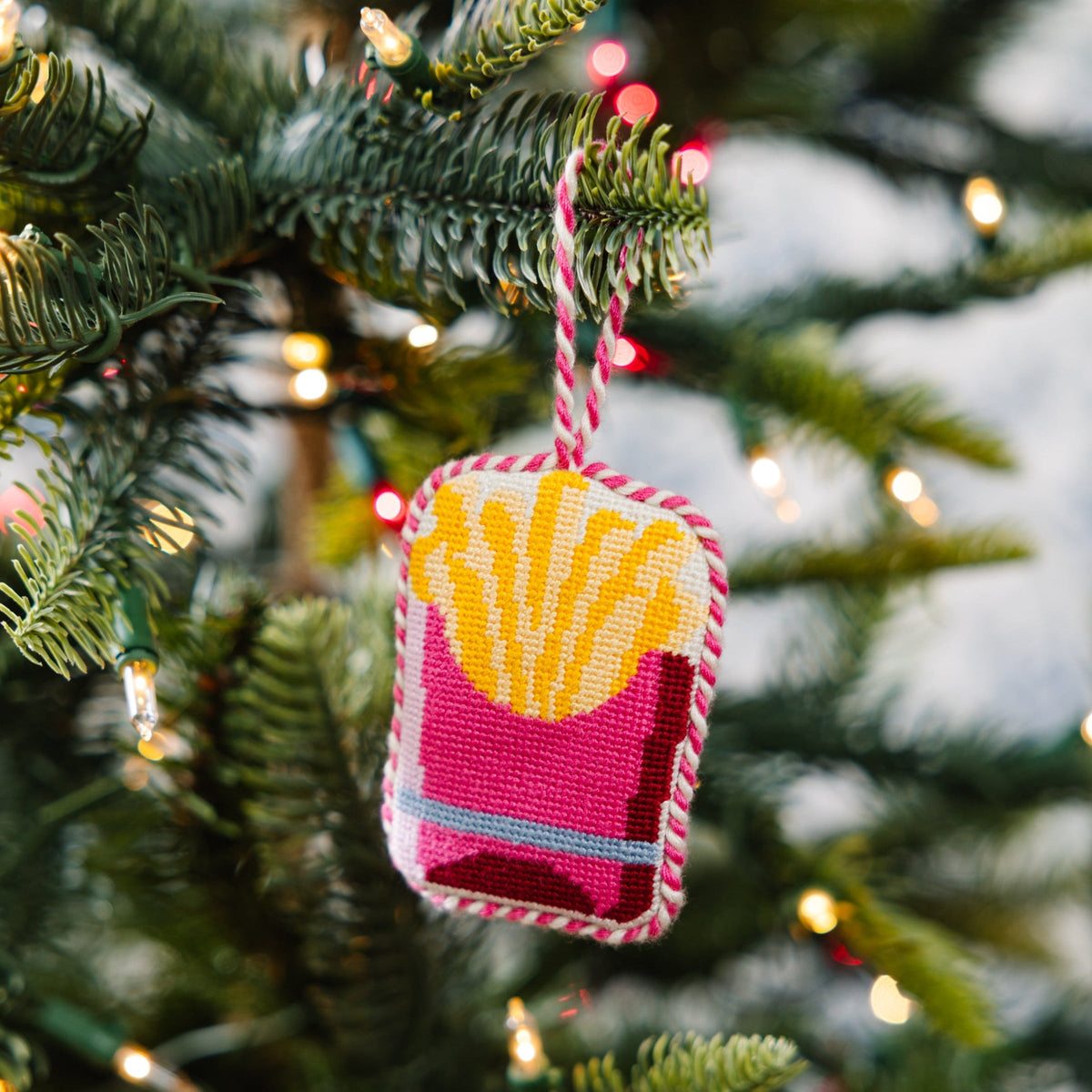 Needlepoint French fries ornament hanging from striped cord, pink and yellow stitched square