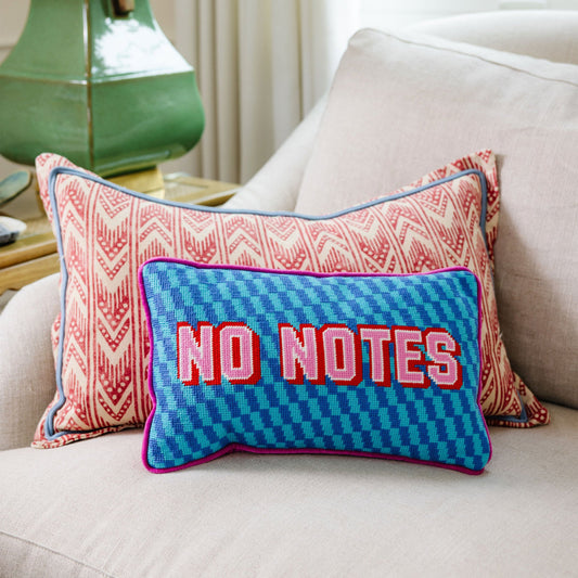 Needlepoint pillow with blue “NO NOTES” embroidery and purple piping on the front