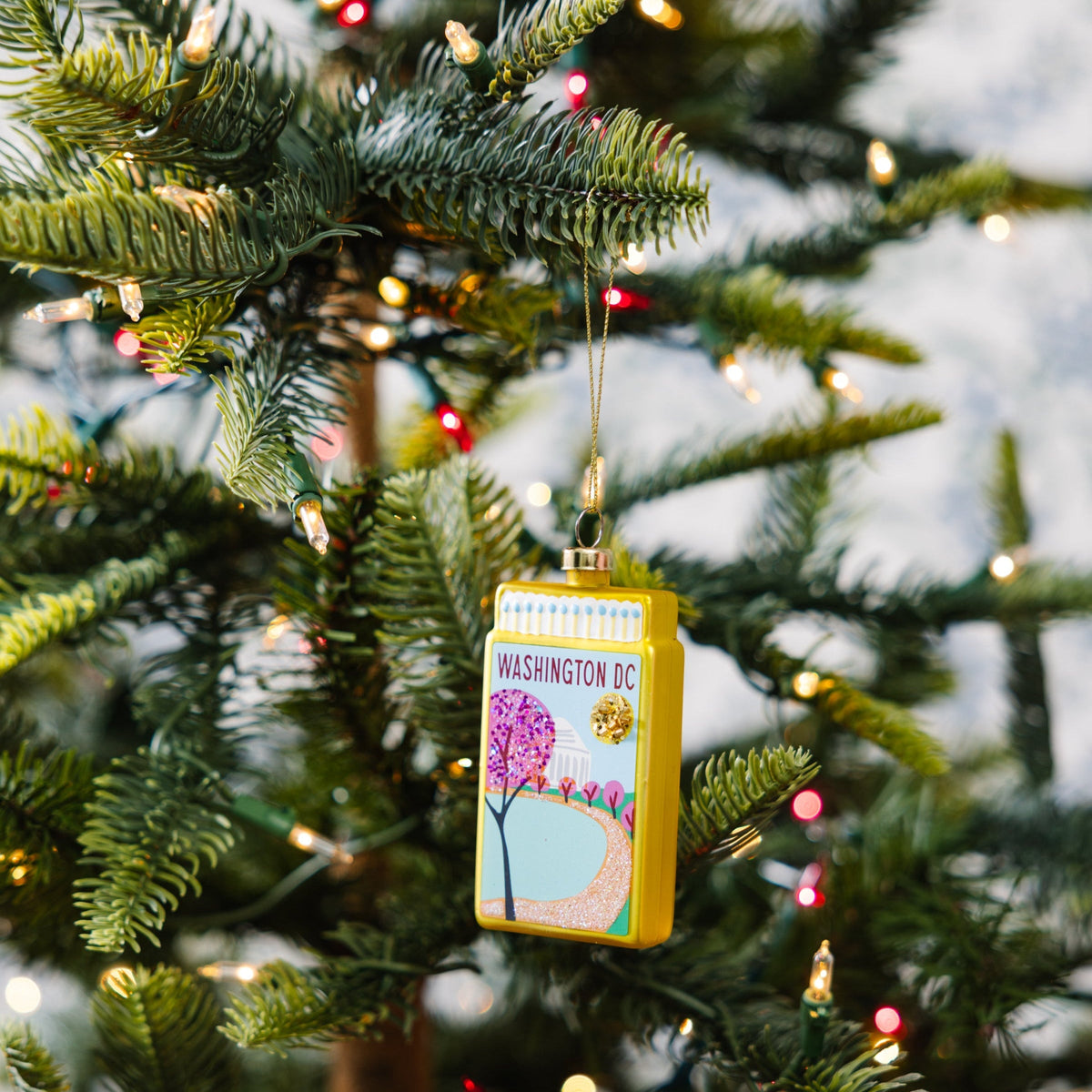 Washington DC matchbook ornament hanging from gold cord on a Christmas tree