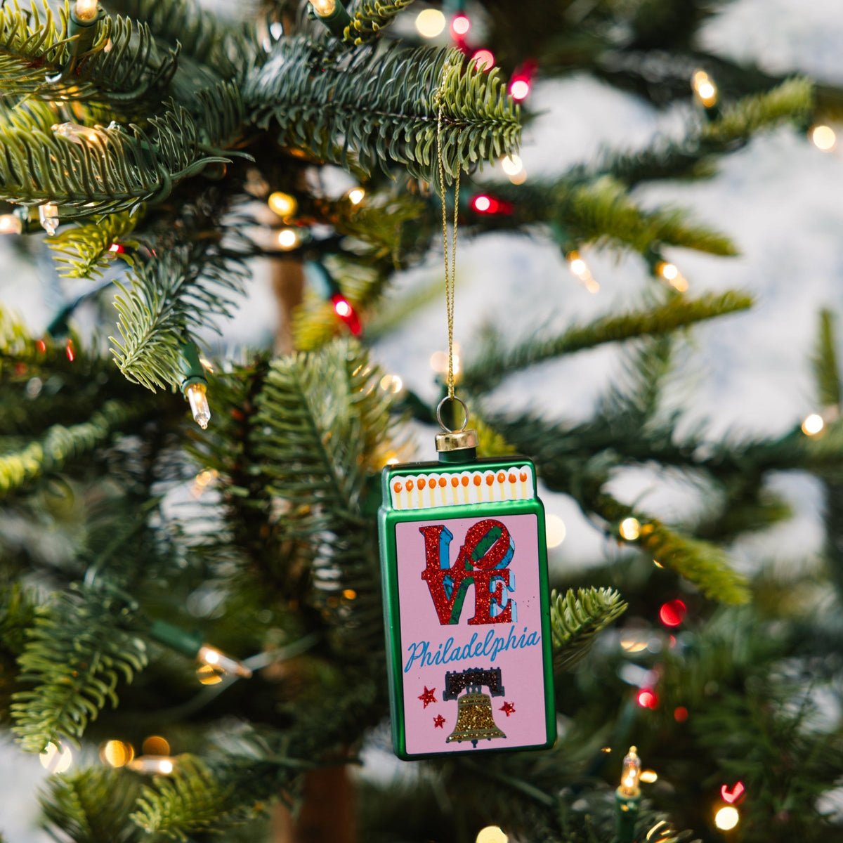 Small matchbook ornament with 'VE' and Philadelphia print hanging on a tree