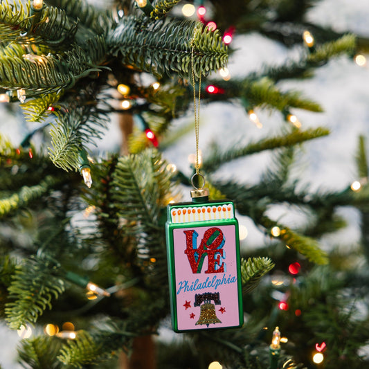 Small matchbook ornament with 'VE' and Philadelphia print hanging on a tree