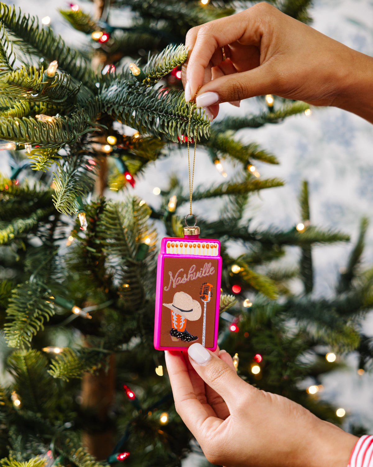 Pink matchbook ornament held while hanging on an evergreen tree