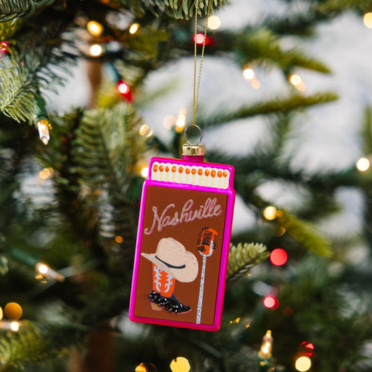 Pink matchbook ornament hanging on a Christmas tree branch