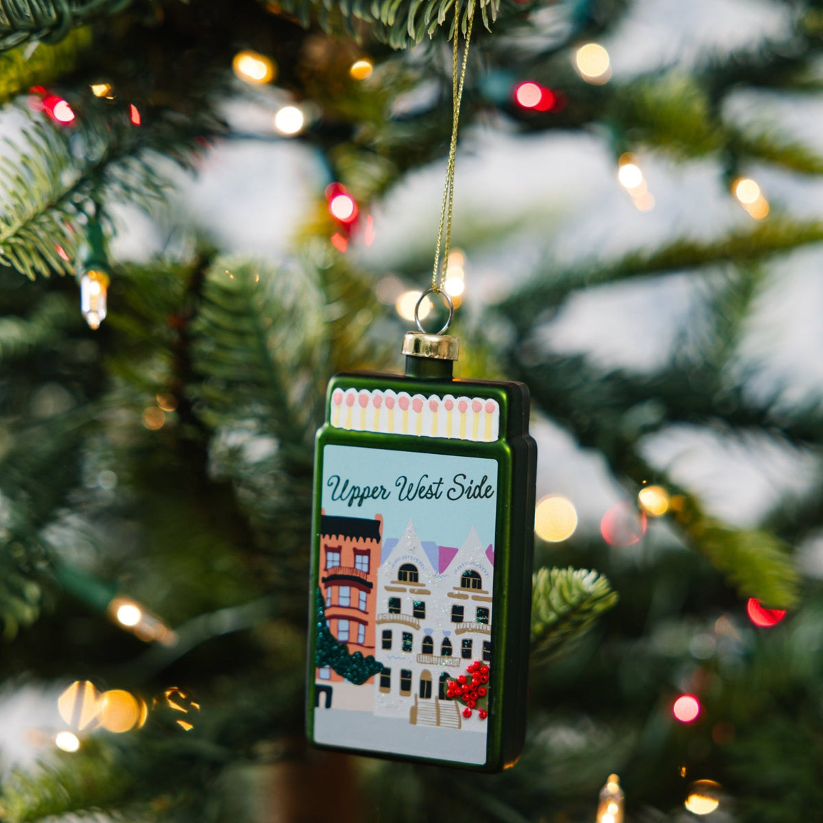 Hanging matchbook ornament with Upper West Side artwork on a Christmas tree