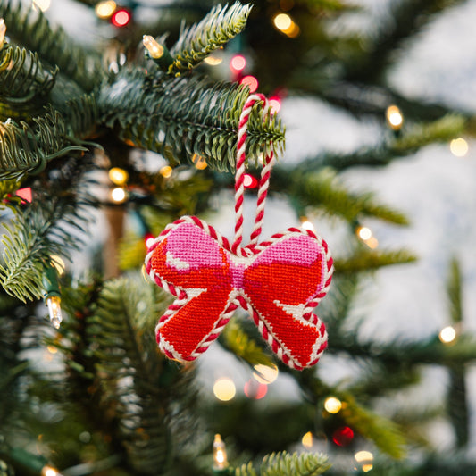 Needlepoint bow ornament hanging from a red-and-white striped cord