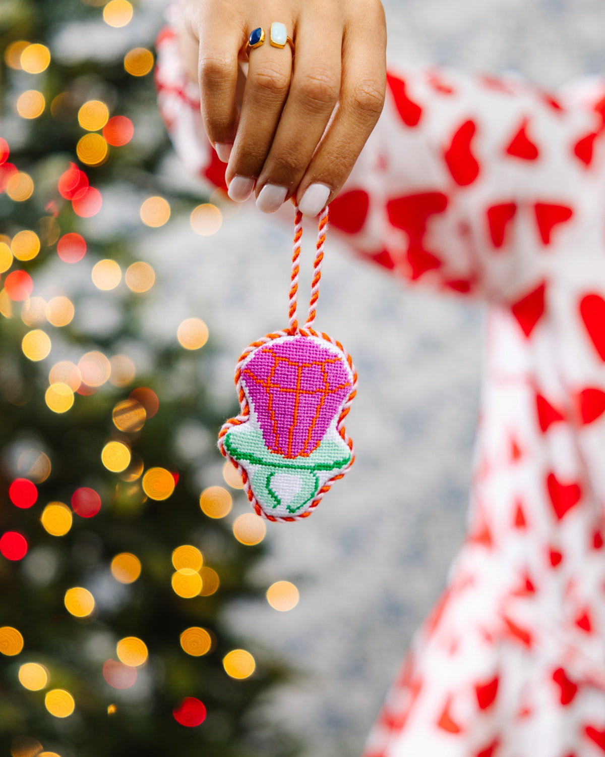 Needlepoint candy ring ornament held by braided cord, pink-purple candy and green base