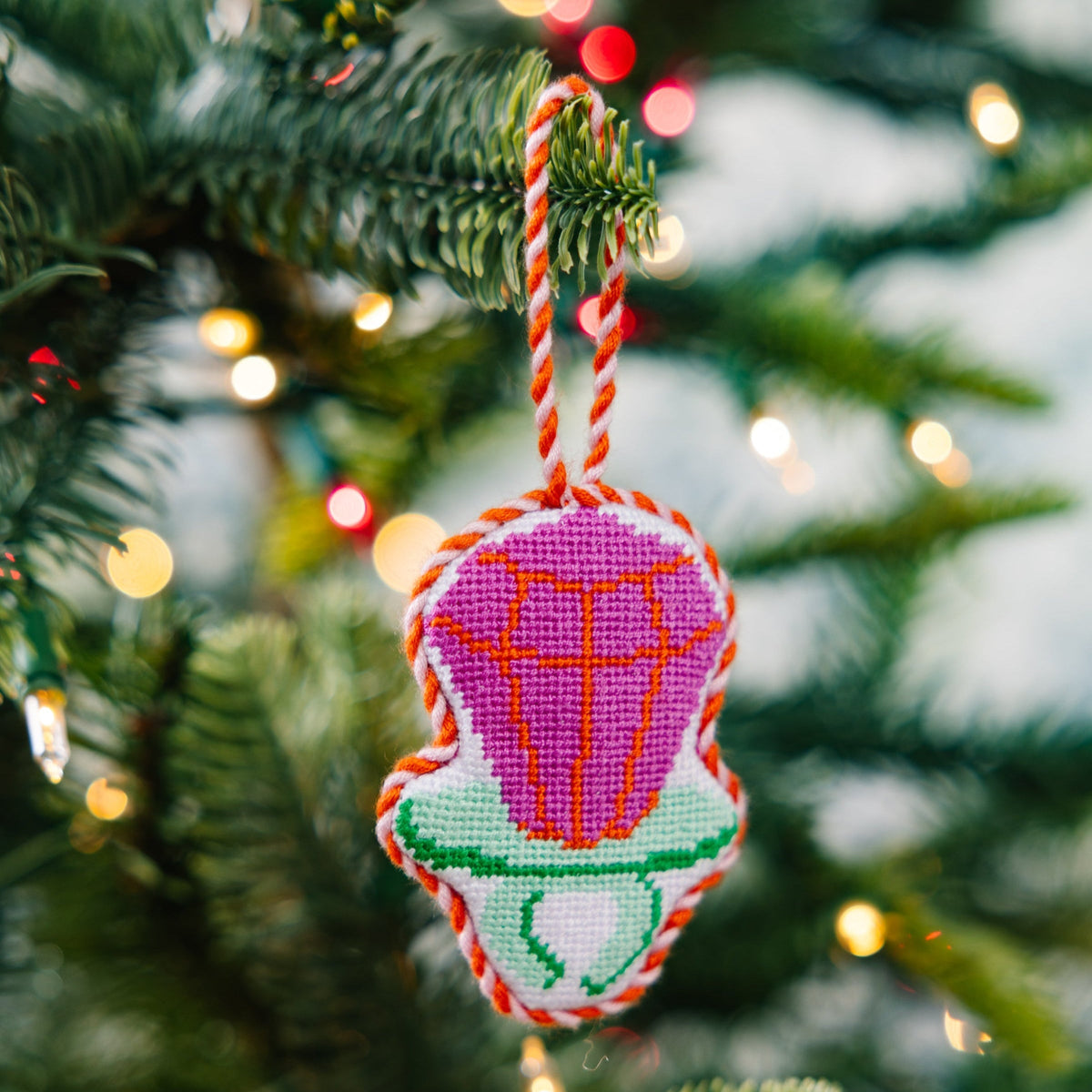 Needlepoint candy ring ornament hanging from tree, pink-purple candy and green base