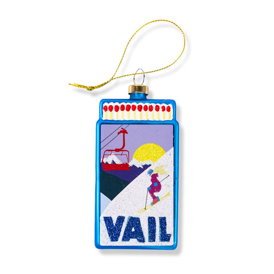 Blue matchbook-style ornament with gold loop, VAIL design and ski scene on front.