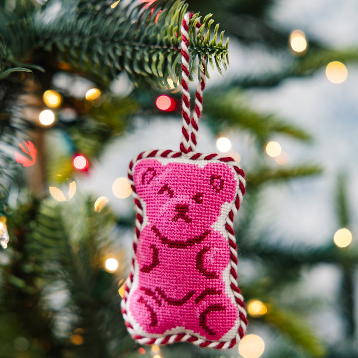 Pink gummy bear needlepoint ornament hanging from a Christmas tree