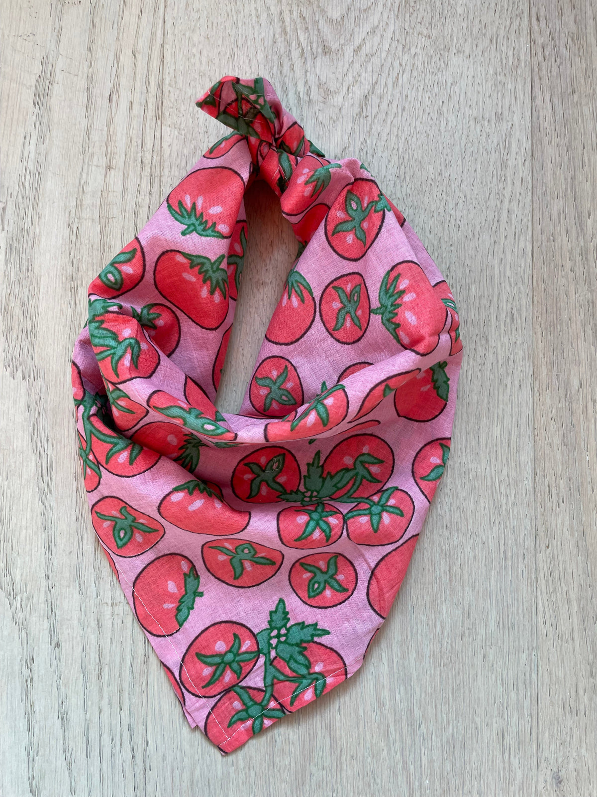 Pink triangle bandana scarf with strawberry pattern, knotted at the top