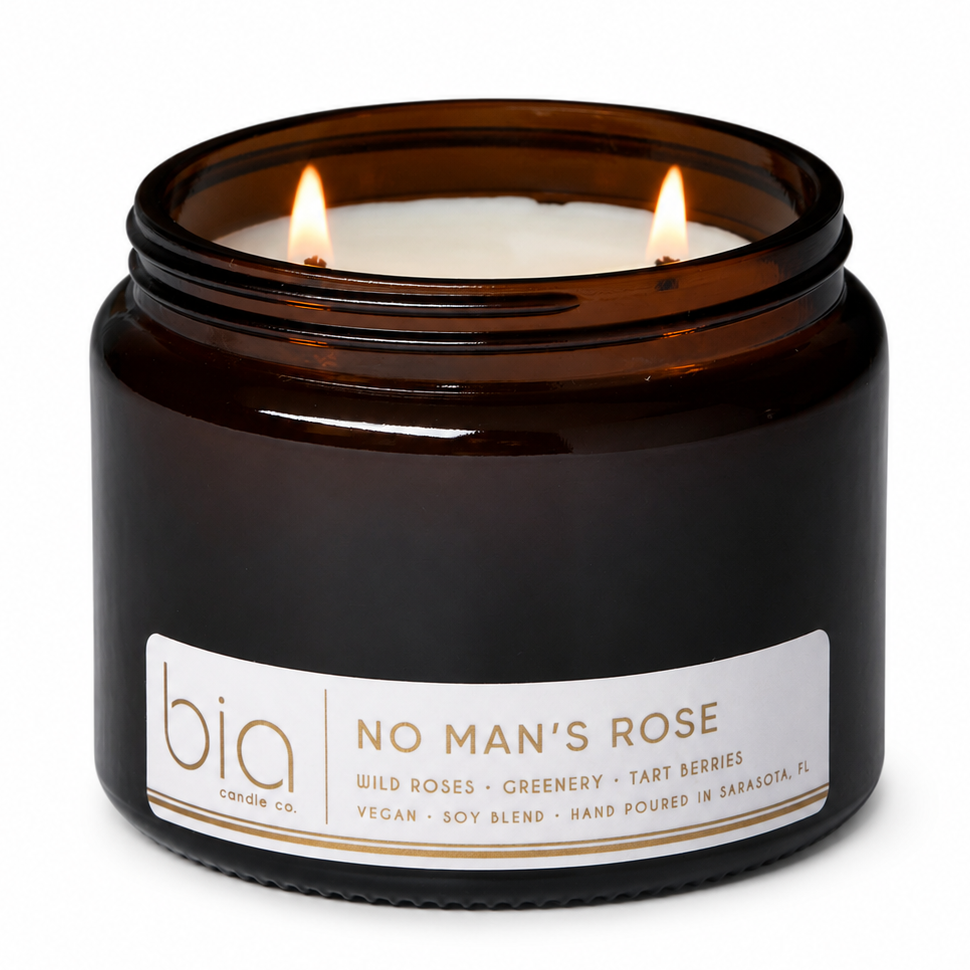 Dark glass soy candle jar with two wicks and white label on front.